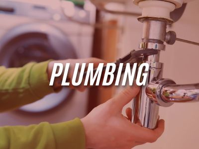 Image with the word "Plumbing" overlaying an image of a person fixing the pipe under a sink with a washing machine in the background.