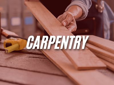 Image with the word "Carpentry" overlaying an image of a person holding a piece of wood before it is going to be cut.